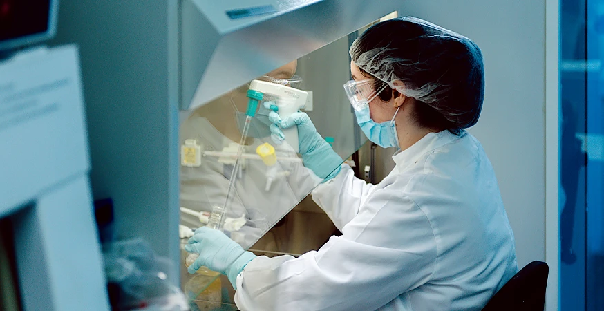 Fresenius Kabi Mitarbeitende*r entnimmt Flüssigkeit von einem kleinem Behälter