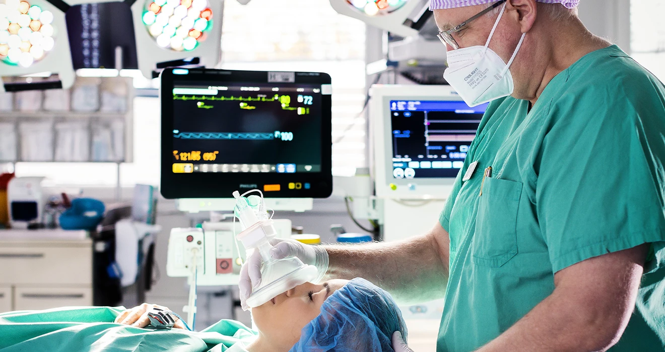 Ein Arzt oder Pfleger beatmet eine Patientin in einem Operationssaal