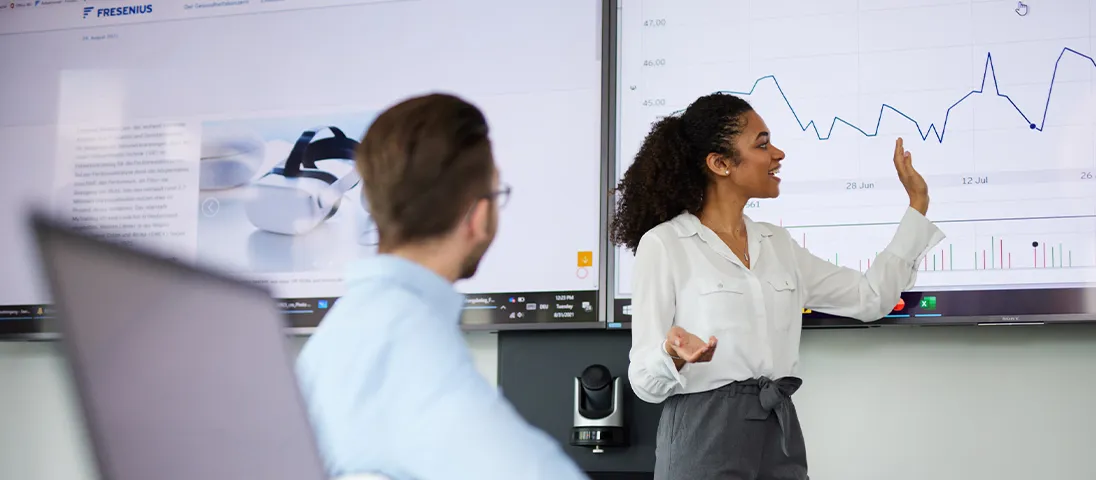 A woman is standing in front of a screen presenting a graph to others