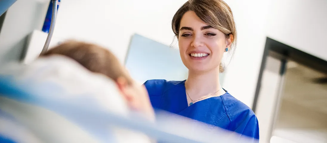 The image shows a healthcare worker smiling to a patient.