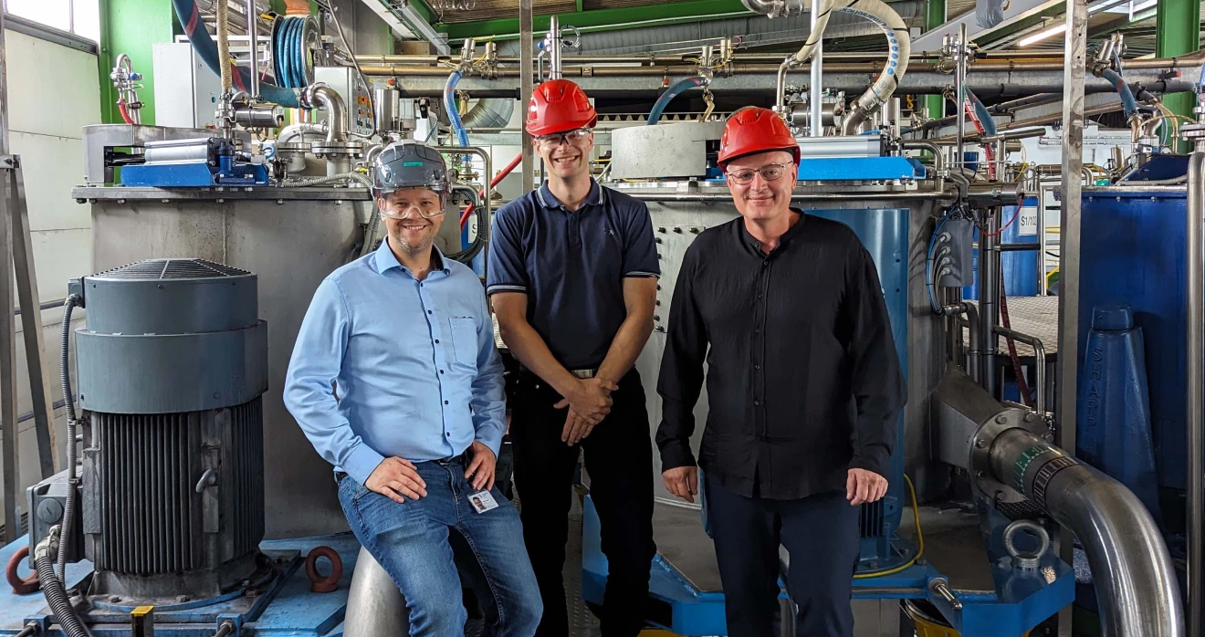Three individuals standing in front of a machinery belonging to the centrifuge in Linz.