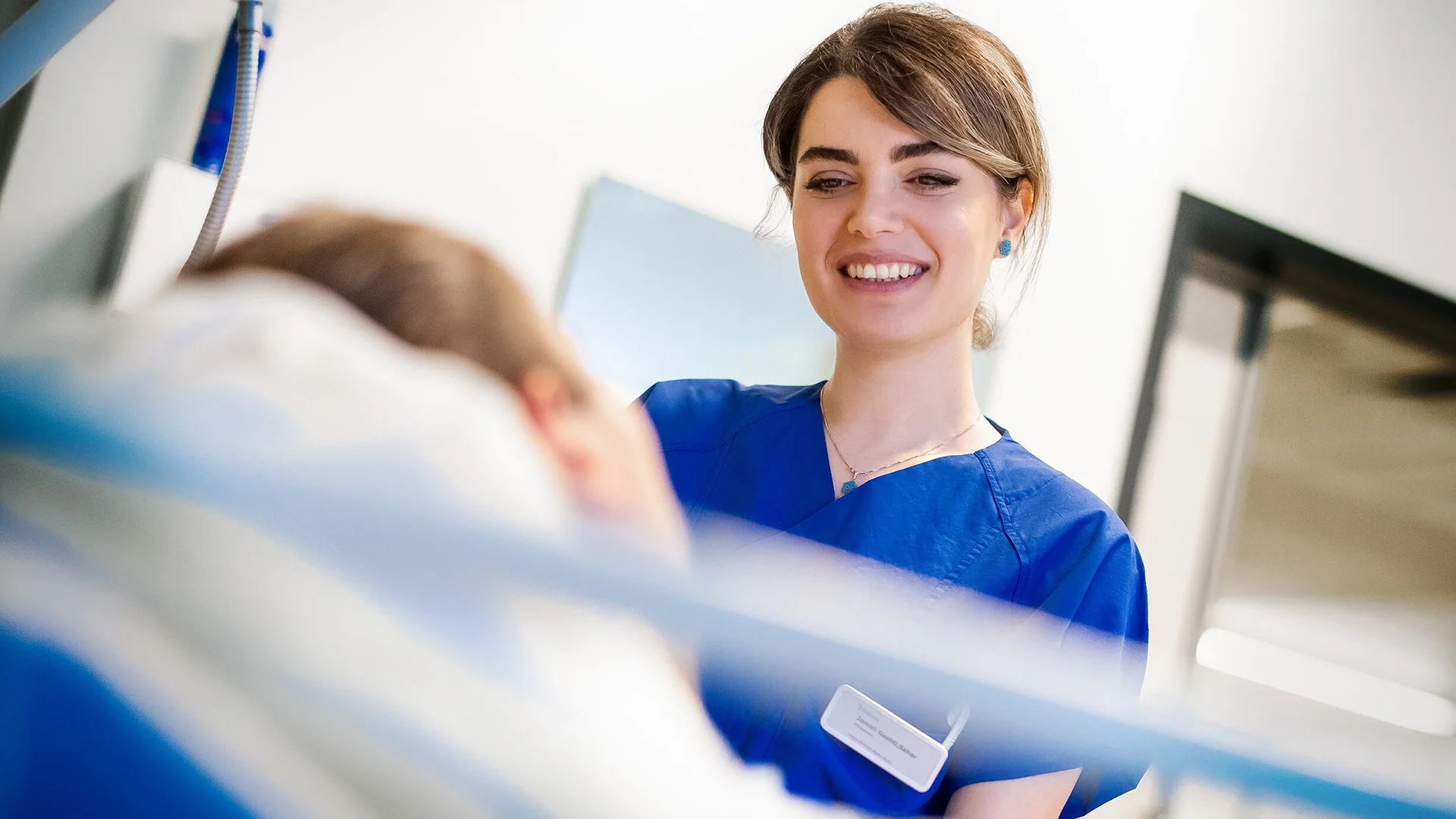 The image shows a healthcare worker smiling to a patient.