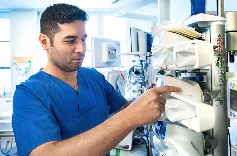 A healthcare worker is engaged with some medical equipment.